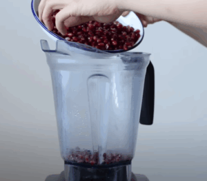 devojka ubacuje očišćen nar u blender