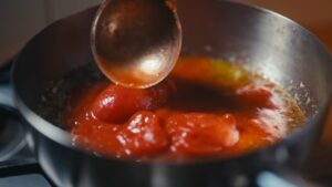 Kuvanje paradajza sa lukom i začinima dok se marinara sos ne zgusne