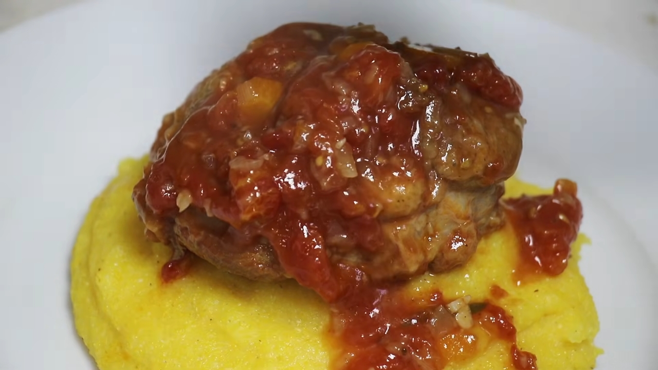 Osso buco u bogatom paradajz sosu poslužen preko kremaste zlatne palente